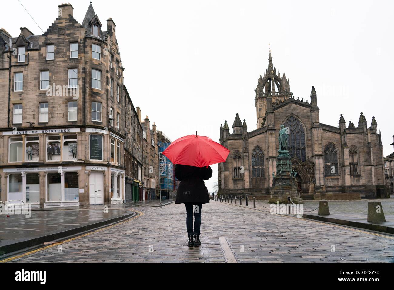 Femme tenant un parapluie rouge sous la pluie sur le Royal Mile dans la vieille ville d'Édimbourg, en Écosse, au Royaume-Uni Banque D'Images