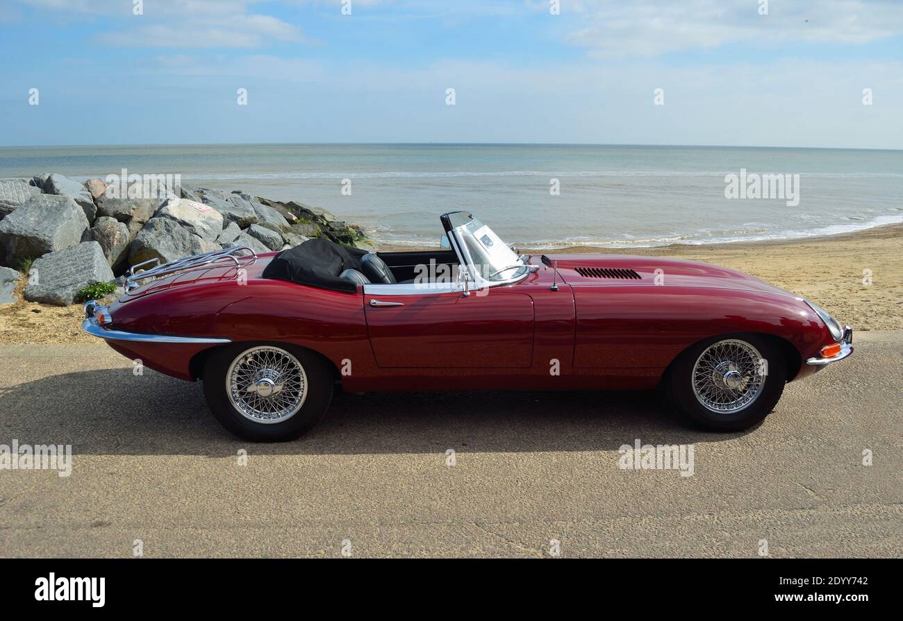 Voiture cabriolet Jaguar E Type rouge classique garée sur la promenade en bord de mer. Banque D'Images