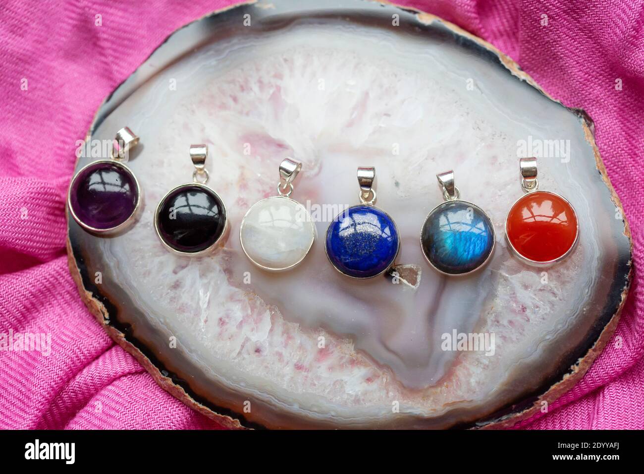 Collection de pendentifs en argent sterling avec diverses pierres minérales agate et fond de texte rose Banque D'Images