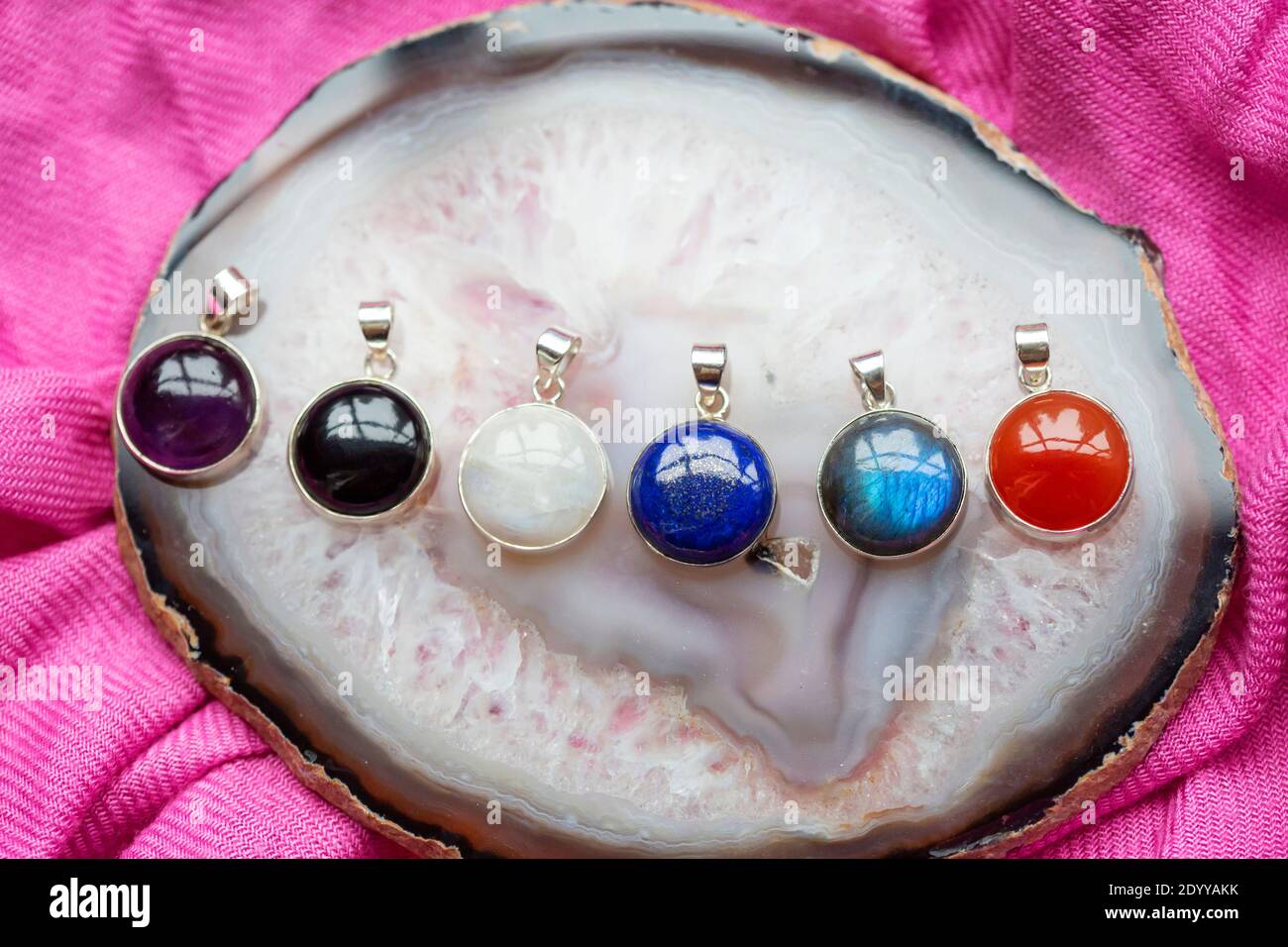 Collection de pendentifs en argent sterling avec diverses pierres minérales agate et fond de texte rose Banque D'Images