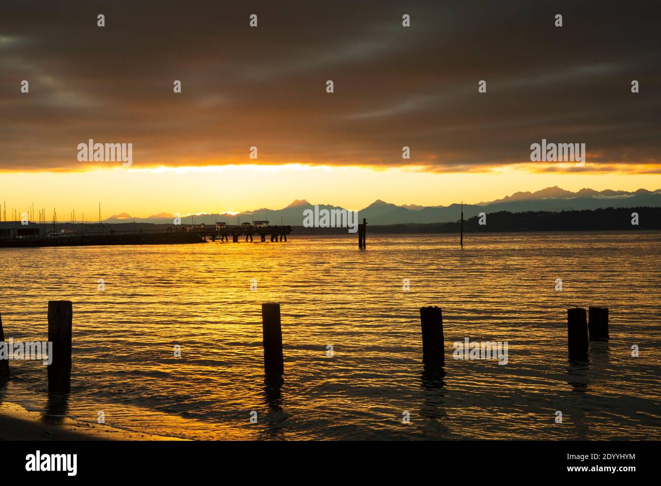 WA18894-00...WASHINGTON - coucher de soleil sur les montagnes olympiques, jetant une lueur sur le Puget Sound depuis la plage d'Edmonds. Banque D'Images