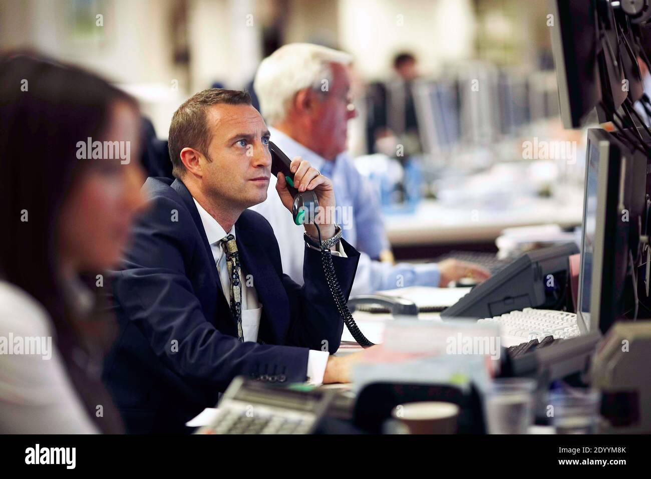 Grande-Bretagne/Londres. UN employé local du trading d'actions parle au téléphone alors qu'il regarde un moniteur de stock Banque D'Images