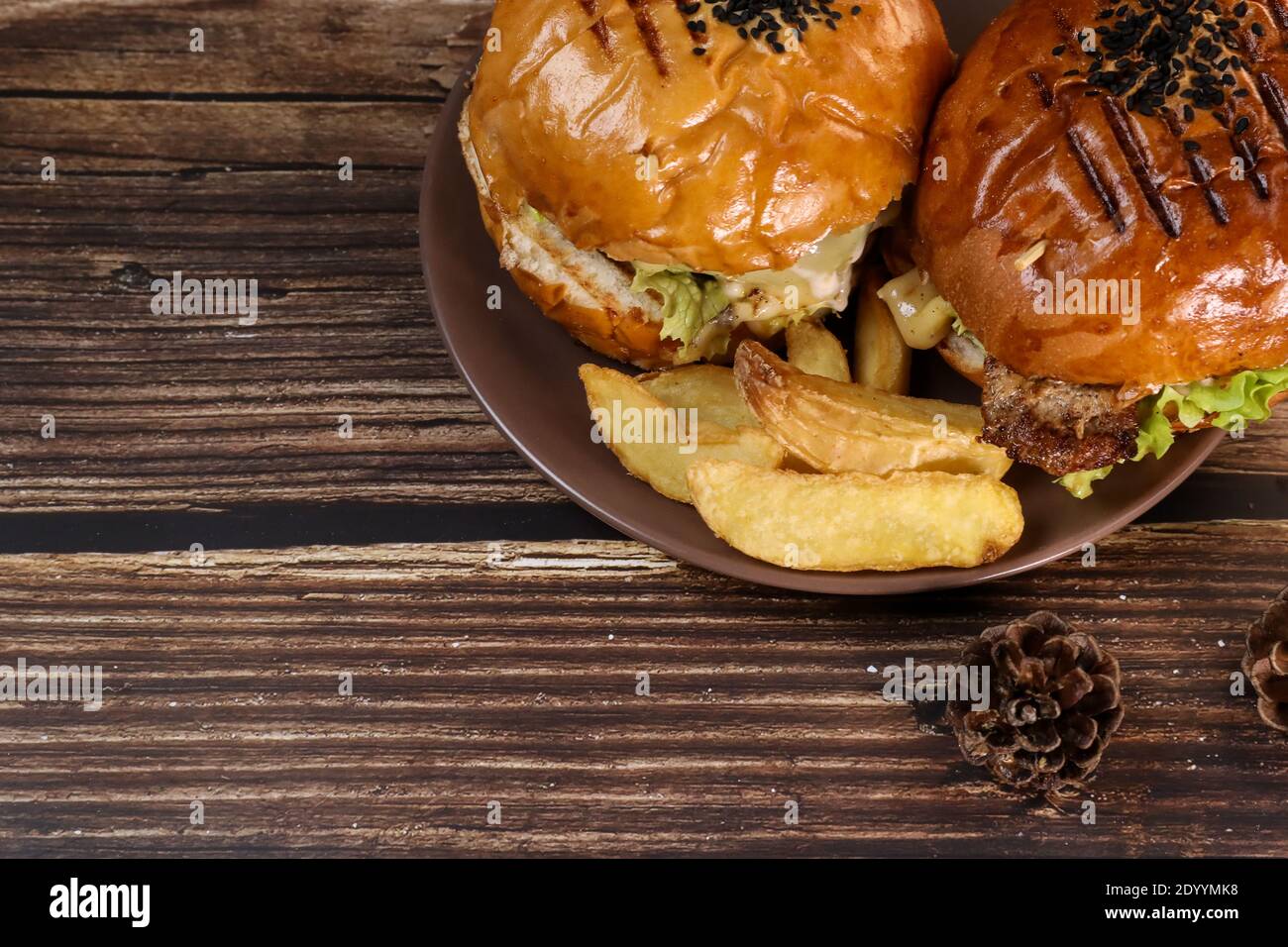 Vue de dessus de deux hamburgers fraîchement frits se trouvent sur une assiette et une table en bois. Dîner frit juteux. Banque D'Images