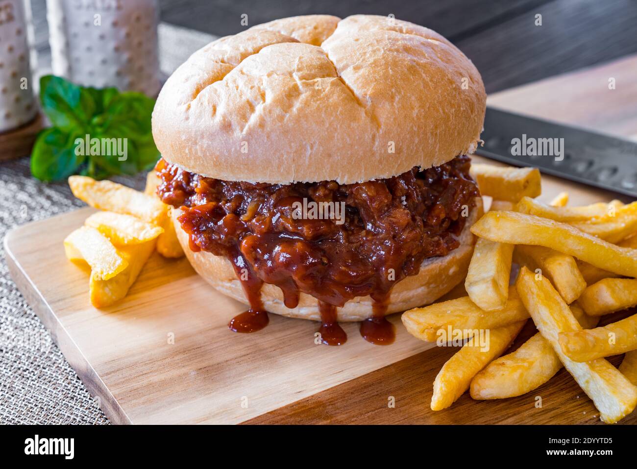 Sandwich barbecue au porc chaud et frais avec pommes de terre frites sur une planche à découper Banque D'Images