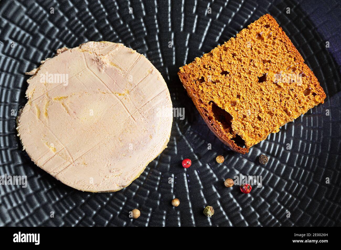 Foie gras de canard, pain d'épice et grains de poivre sur une assiette noire Banque D'Images