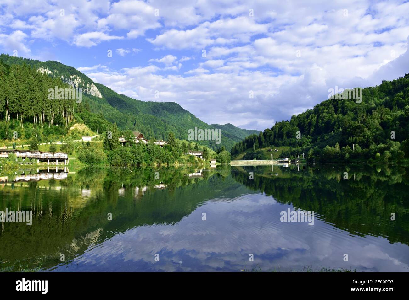 Paysage de montagnes, ciel nuageux et forêt d'arbres verts se reflète dans le lac. Panorama dans l'eau. Banque D'Images