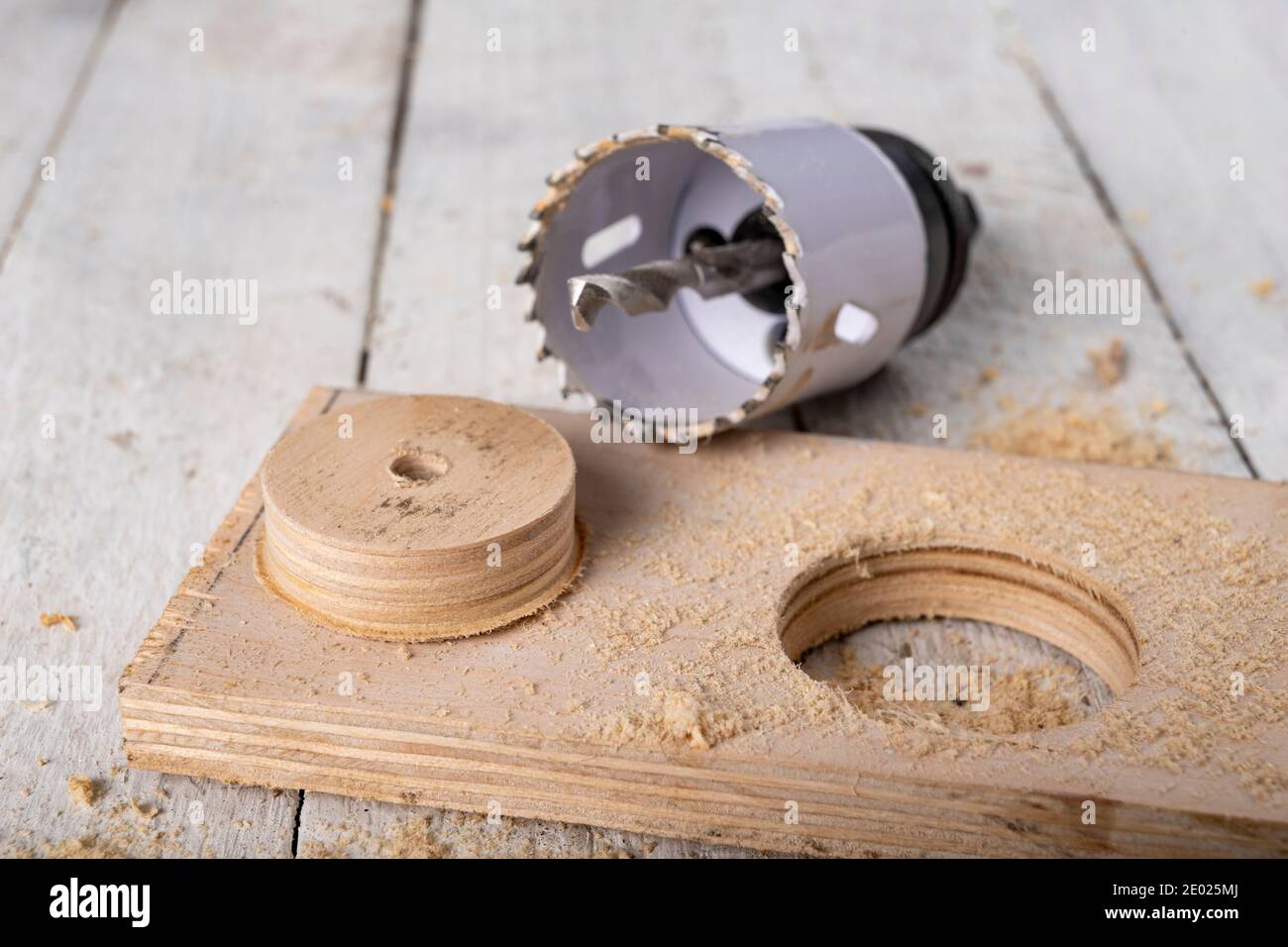 Perçage de scie-cloche métallique dans un morceau de bois. Faire des trous  dans un atelier de menuiserie. Arrière-plan sombre Photo Stock - Alamy