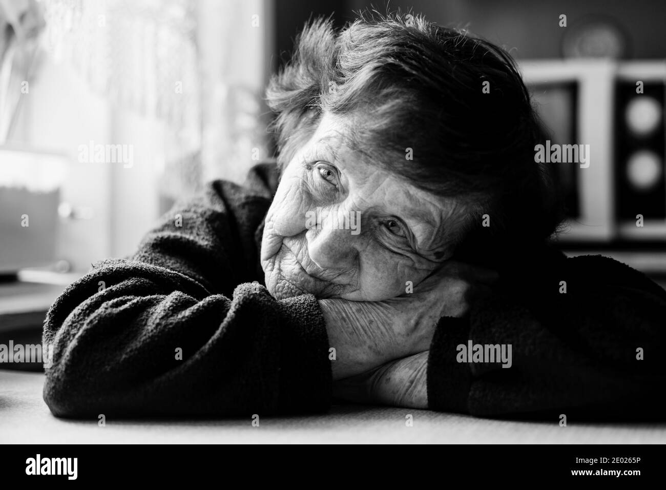 Portrait rapproché d'une vieille femme dans sa maison. Photo en noir et blanc. Banque D'Images