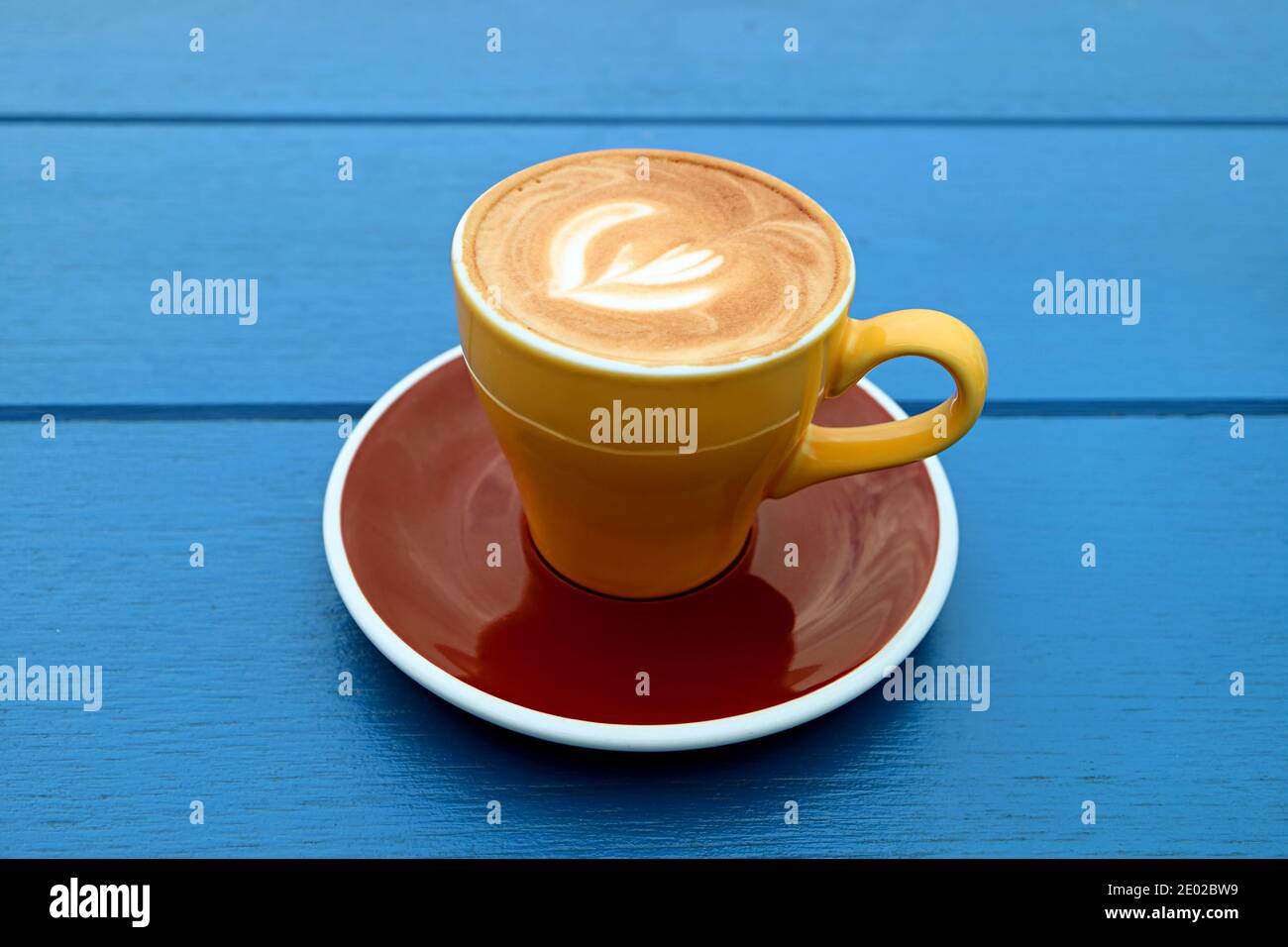 Cappuccino café dans une tasse jaune marron isolé sur bois bleu tableau Banque D'Images