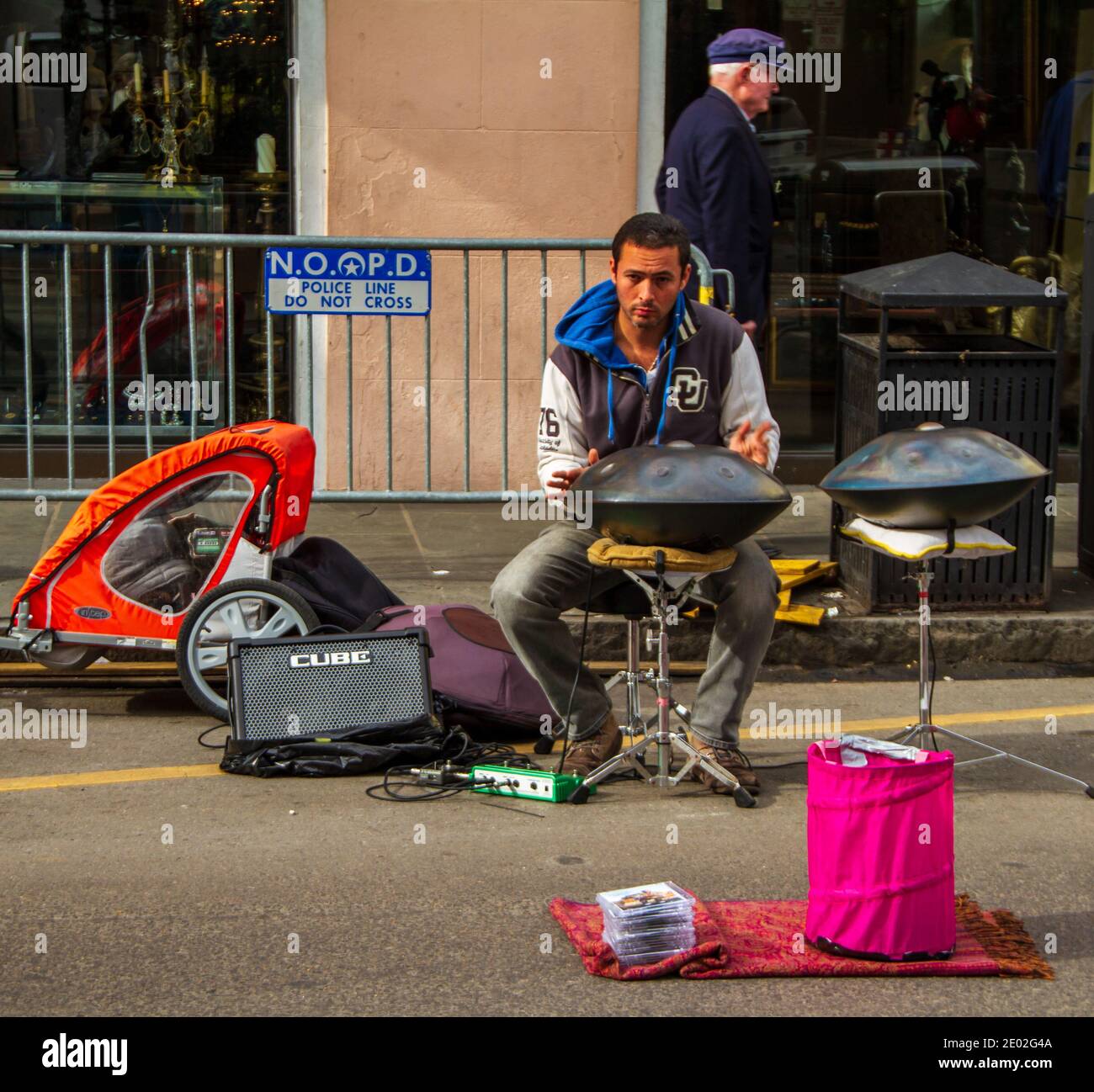 Cet homme joue un tambour à main en métal dans la rue de la Nouvelle-Orléans, dans le quartier français. L'affiche indique la ligne de police, ne pas traverser. Homme âgé marchant. Banque D'Images