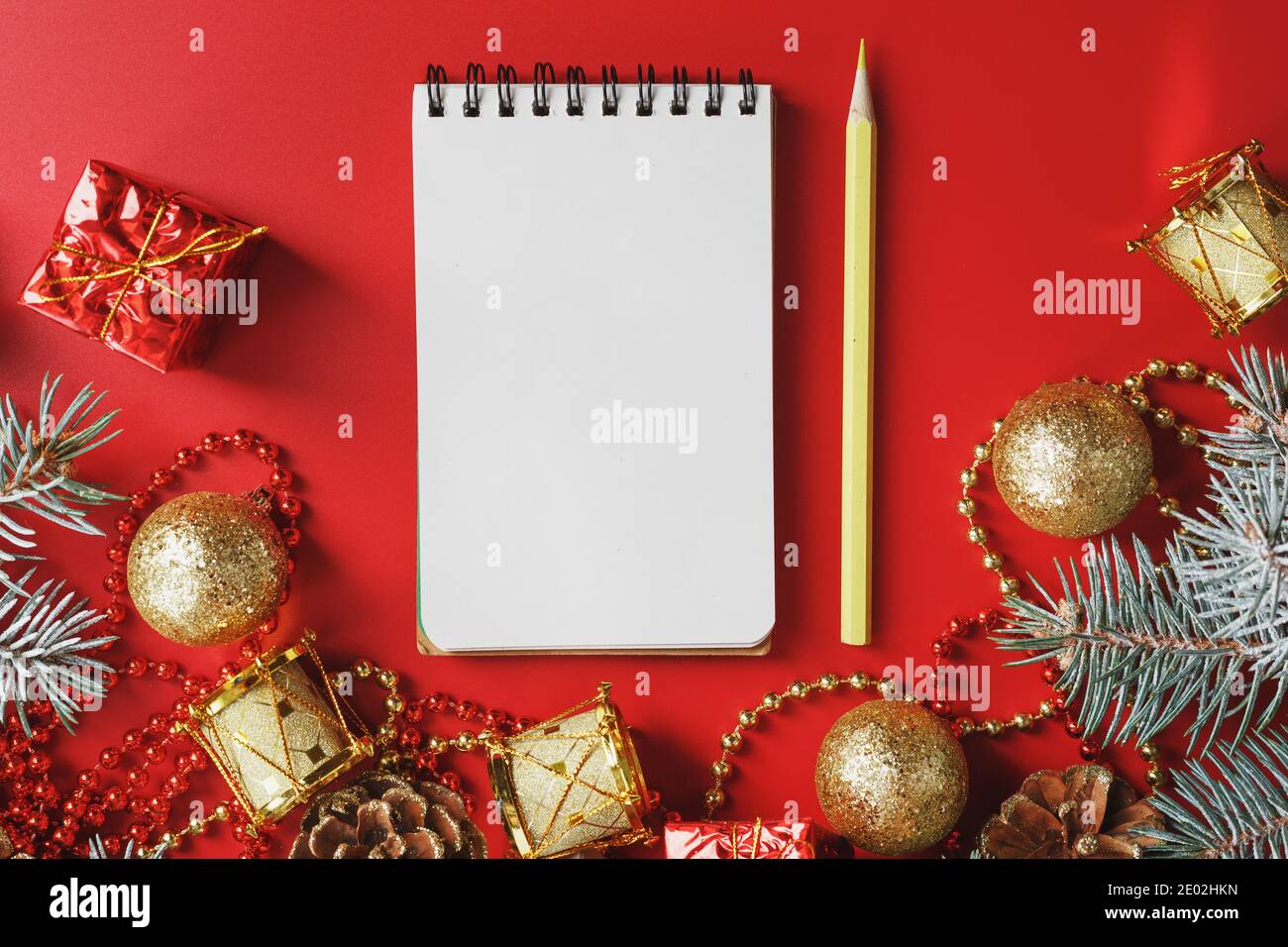 Bloc-notes et crayon pour écrire des voeux et des cadeaux pour le nouvel an et Noël autour des décorations d'arbre de Noël sur un fond rouge. Nouvel an moo Banque D'Images