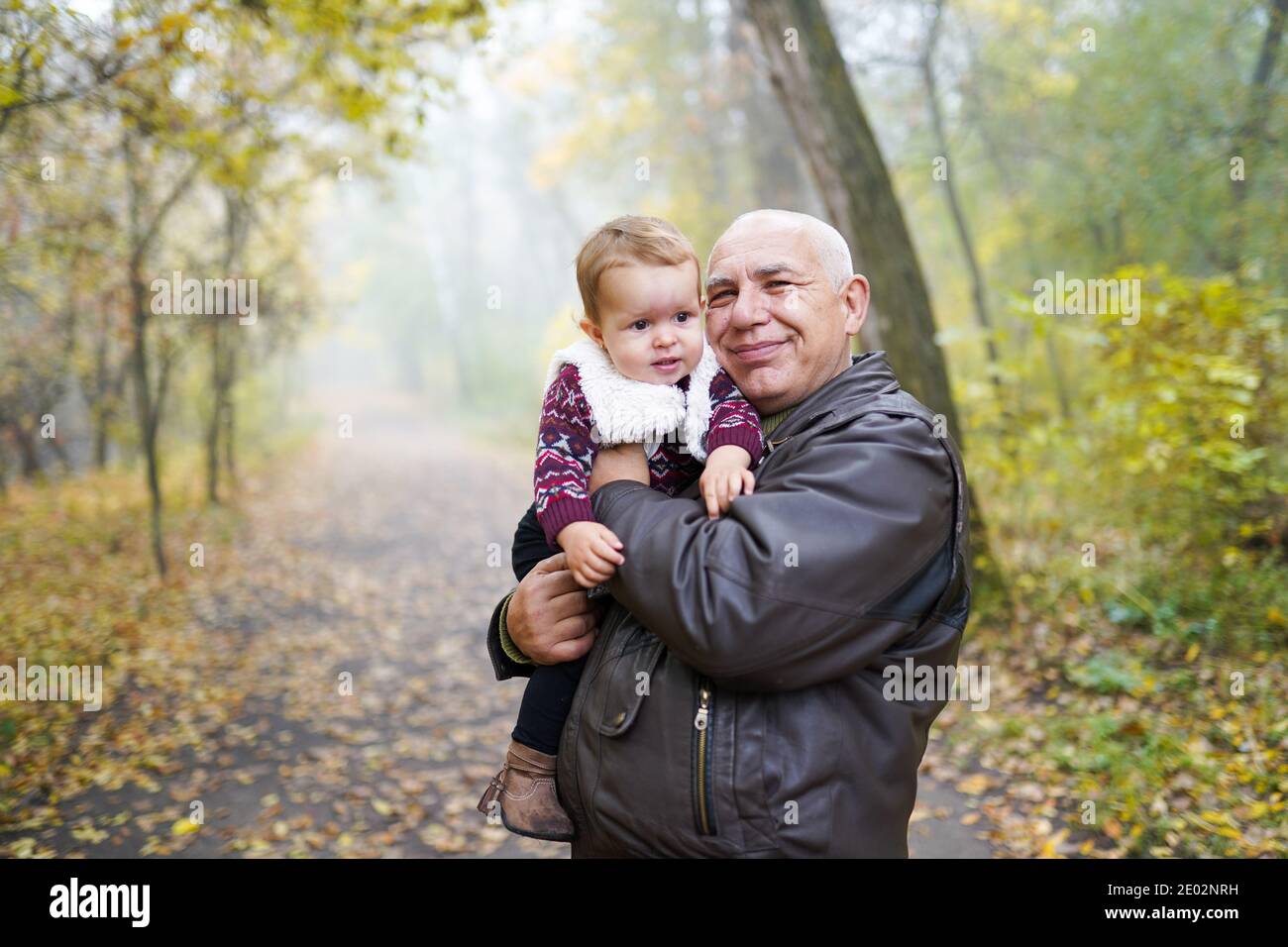 Grand-père heureux tenant un petit-bébé mignon dans le parc d'automne Banque D'Images