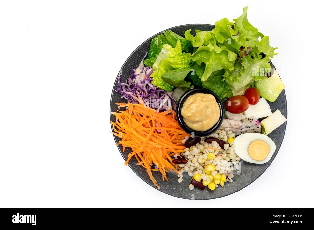 Salade végétale saine de tomates fraîches, carottes, chêne vert, maïs, millet, œuf, chou pourpre et vinaigrette sur assiette noire. Menu régime. Végétalien Banque D'Images