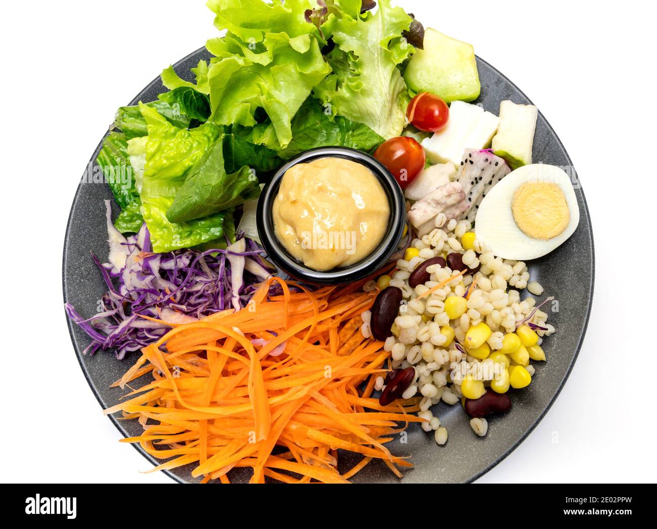 Salade végétale saine de tomates fraîches, carottes, chêne vert, maïs, millet, œuf, chou pourpre et vinaigrette sur assiette noire. Menu régime. Végétalien Banque D'Images