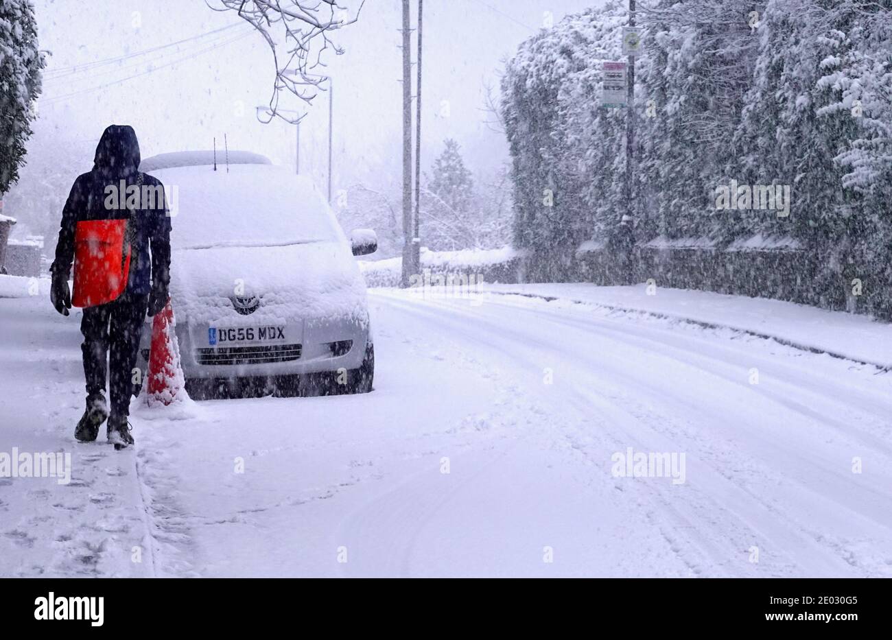 Un paper-boy sur ses rounds un matin enneigé à New Mills, Derbyshire. Banque D'Images