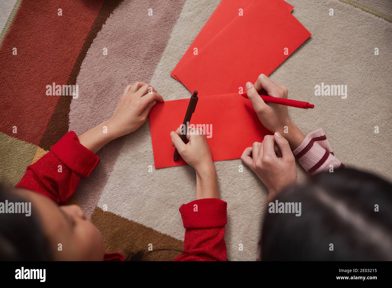 Directement depuis la photo ci-dessus des enfants chinois couchés sur le sol commencer à décorer des enveloppes faites à la main en dessinant quelque chose sur elles Banque D'Images