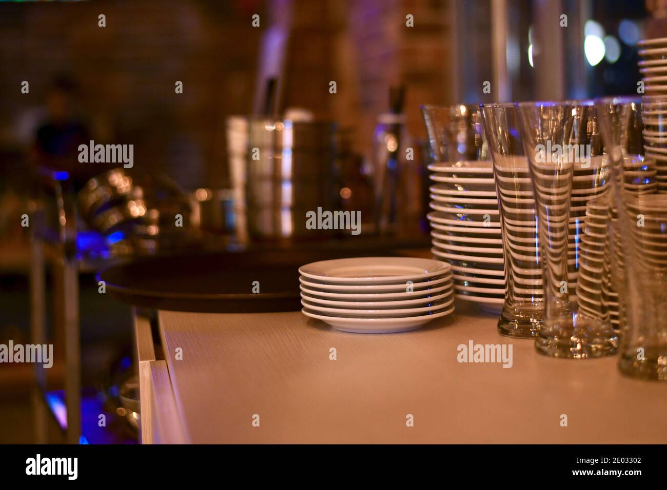 Piles de plats propres sur la table du bollard. Plaques et soucoupes en céramique blanche, verres transparents en verre. Banque D'Images