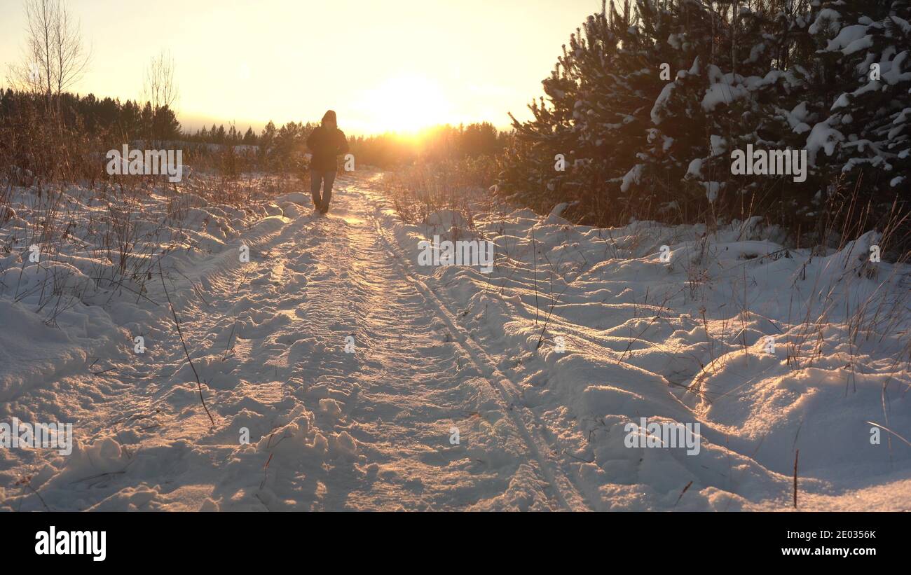 Marchez sur la piste de neige jusqu'au coucher du soleil. L'homme marche dans la neige au soleil Banque D'Images