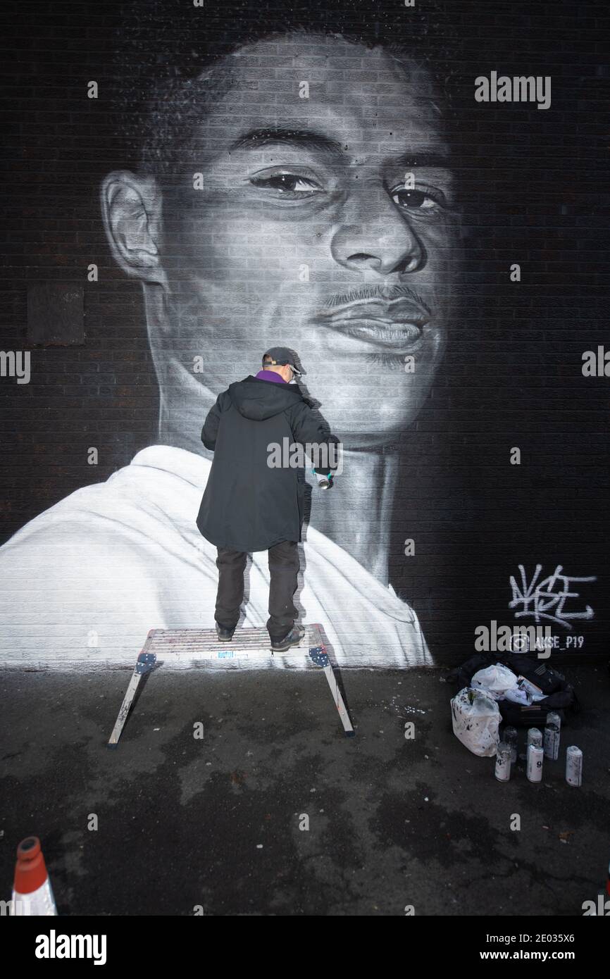 L'artiste de rue Akse, se dresse devant sa fresque de la star du football Marcus Rashford. Banque D'Images