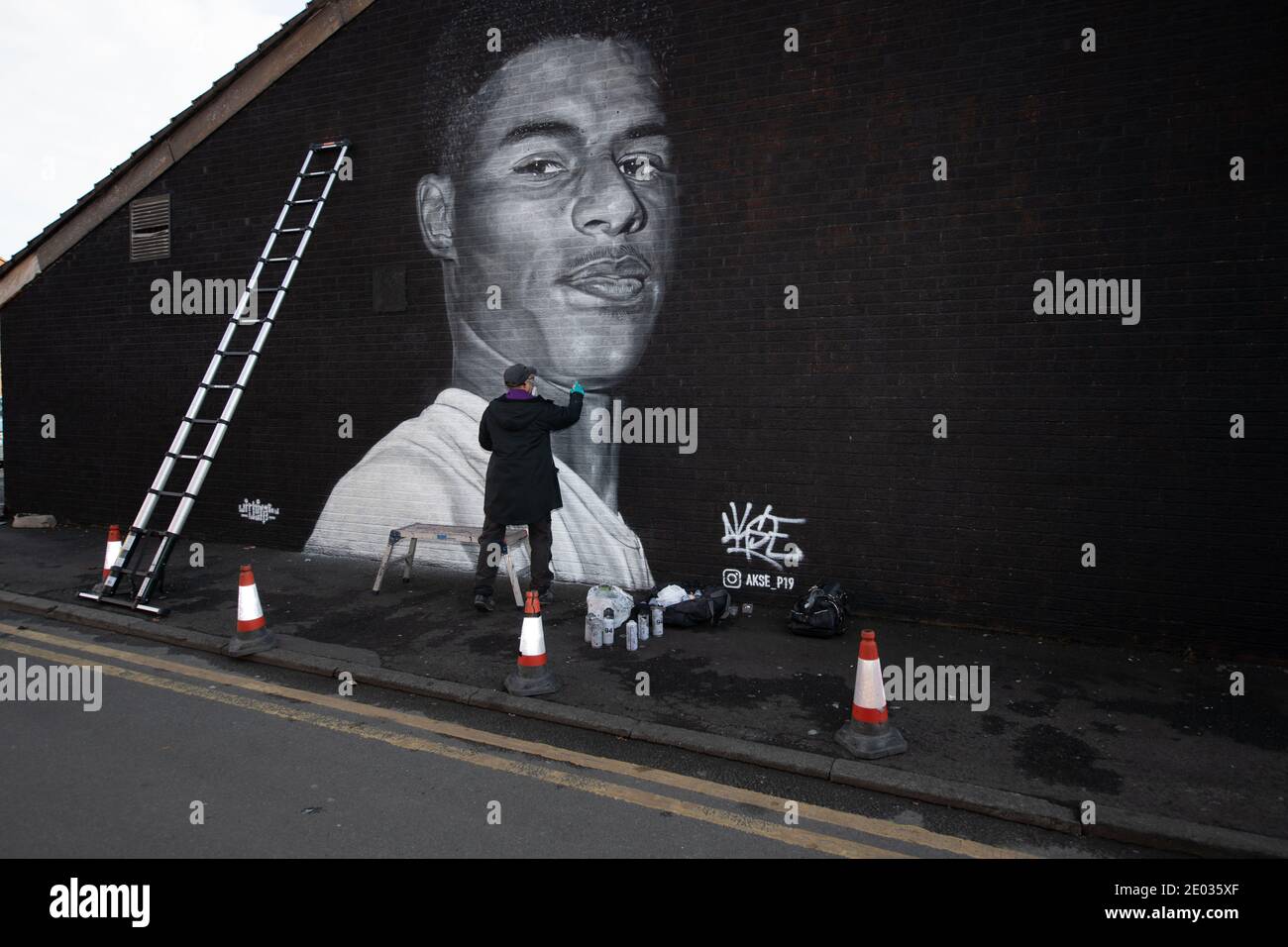 L'artiste de rue Akse, se dresse devant sa fresque de la star du football Marcus Rashford. Banque D'Images