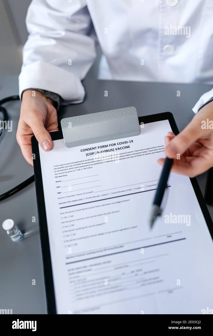 Médecin méconnaissable offrant un stylo pour signer le formulaire de consentement au vaccin contre le coronavirus Banque D'Images