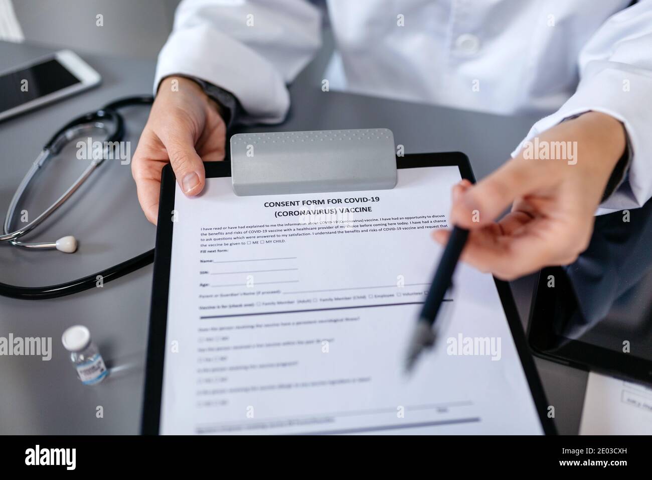 Médecin méconnaissable offrant un stylo pour signer le formulaire de consentement au vaccin contre le coronavirus Banque D'Images