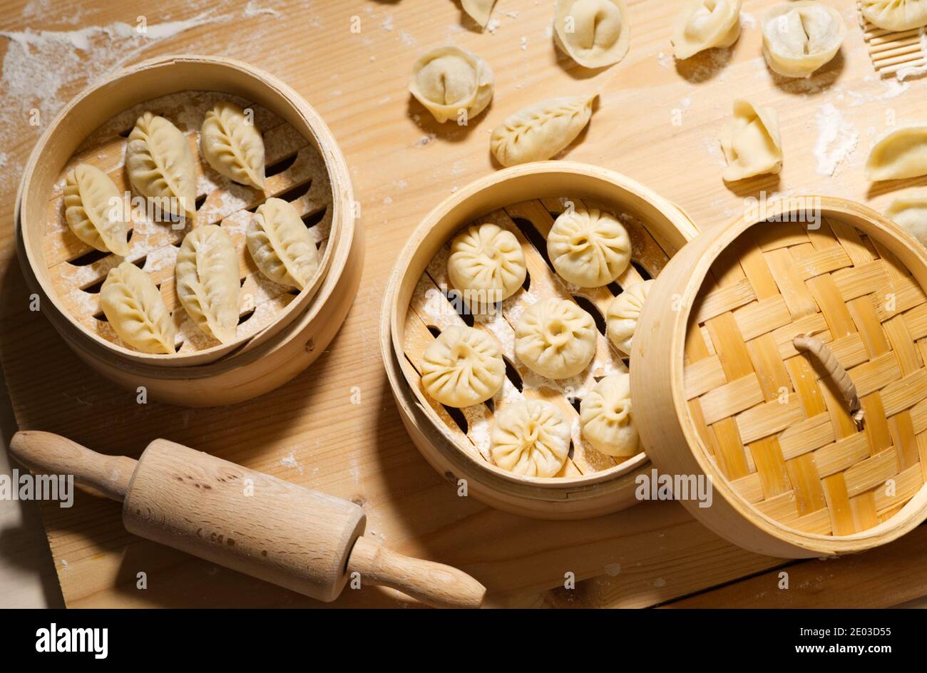 Petits pains et boulettes dans un cuiseur vapeur en bambou, plats faits à la main crus, en-cas chinois maison Banque D'Images