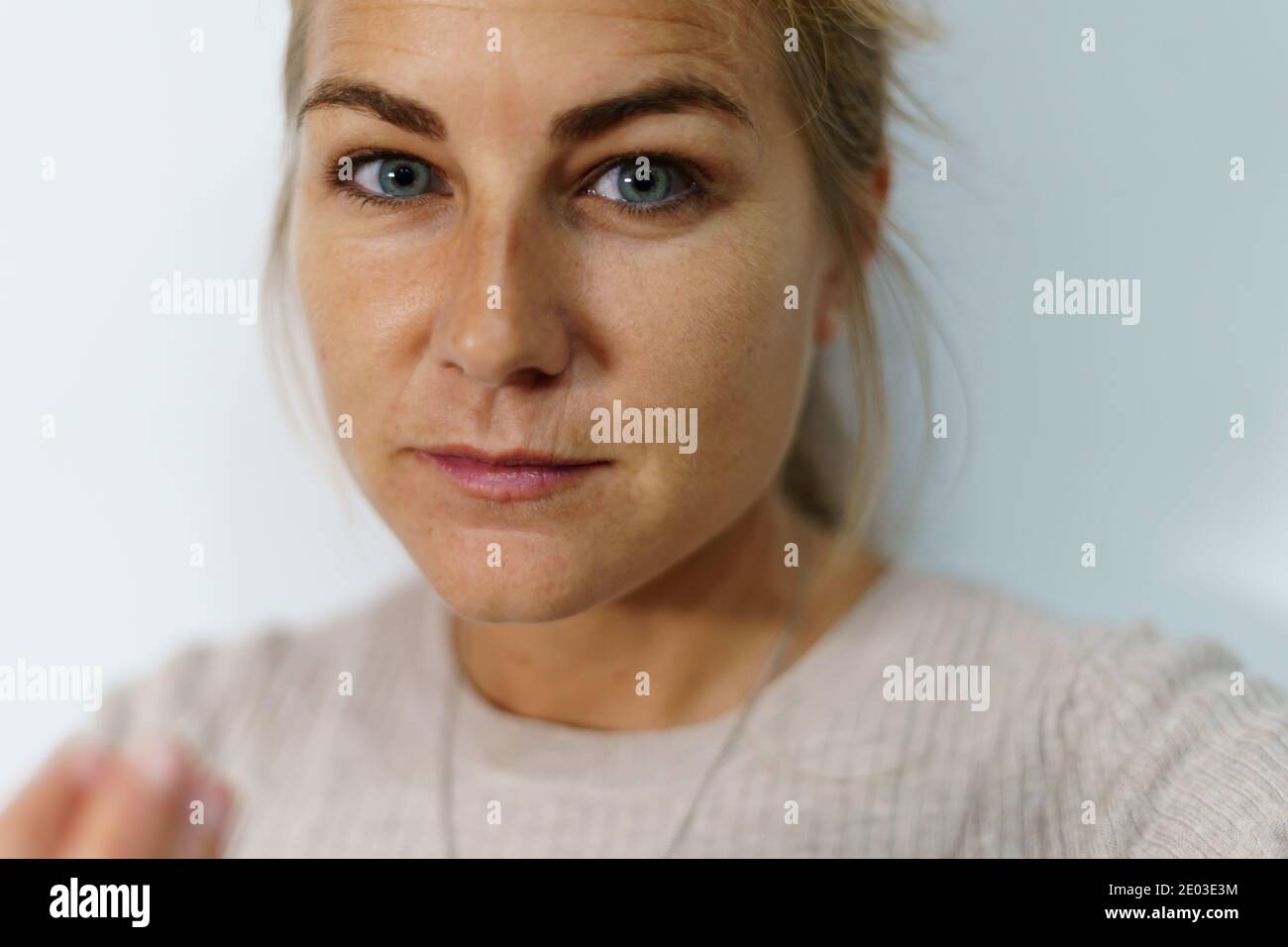 Attention sélective sur le visage d'une femme blonde avec yeux bleus avec des cercles sombres sous ses yeux et un un visage fatigué tout en regardant l'appareil photo avec un coup Banque D'Images
