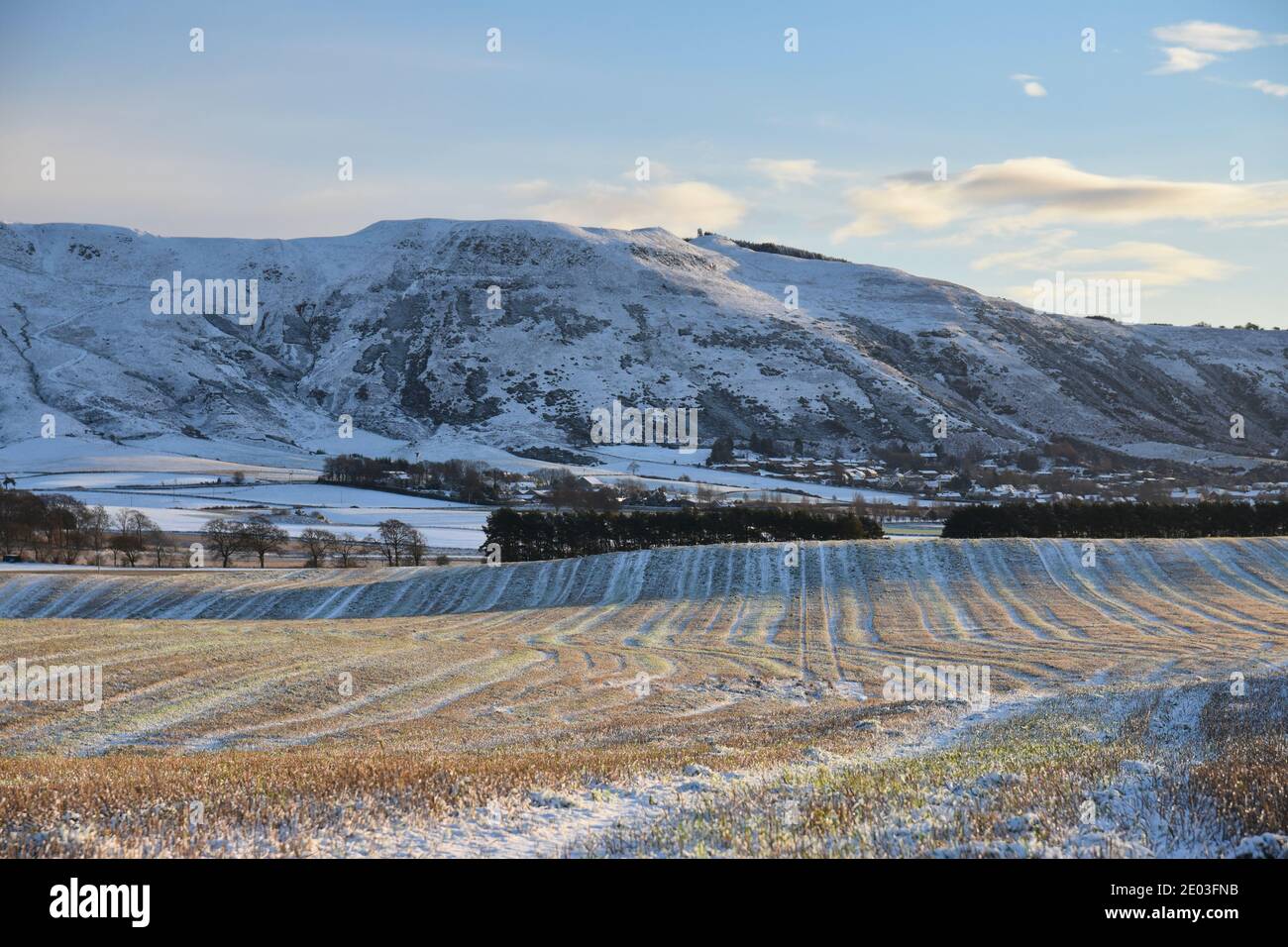 Scène hivernale enneigée de Bishop Hill à Fife, en Écosse, au Royaume-Uni avec champ de ferme en premier plan. Ciel bleu et nuages. Banque D'Images