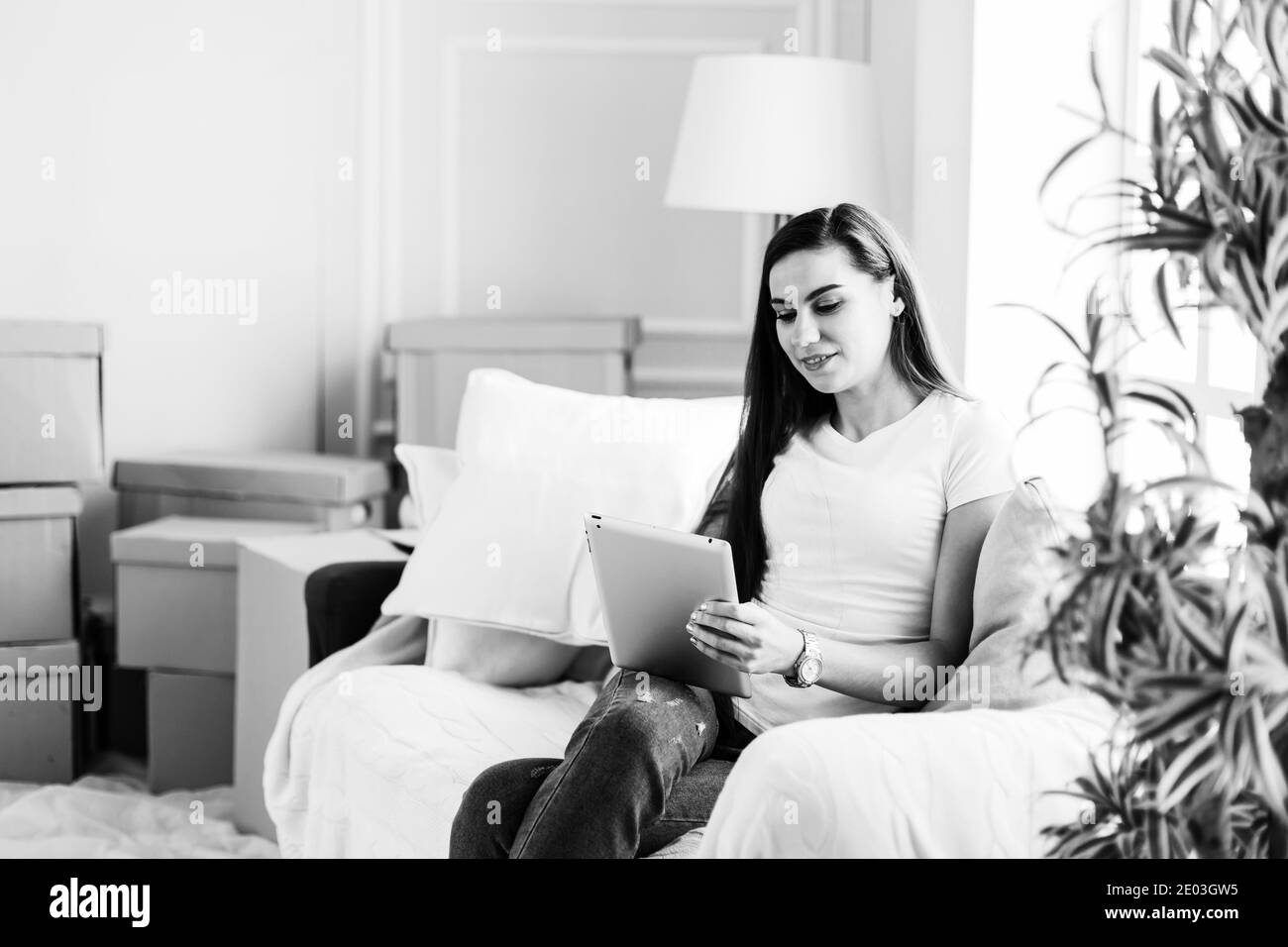 jeune femme avec tablette numérique assis sur un canapé confortable Banque D'Images