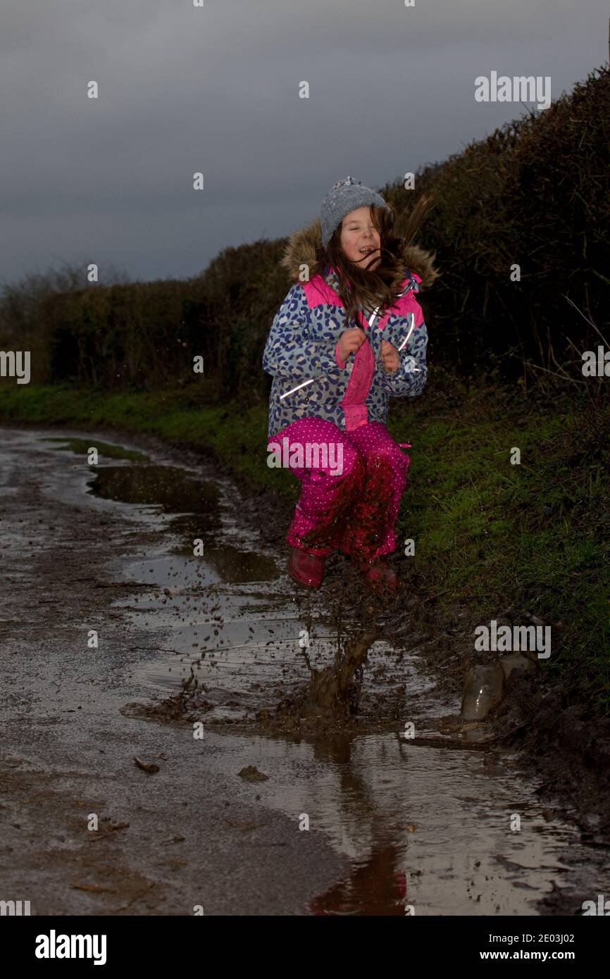 Une jeune fille sautant dans des flaques boueuses. Angleterre Banque D'Images