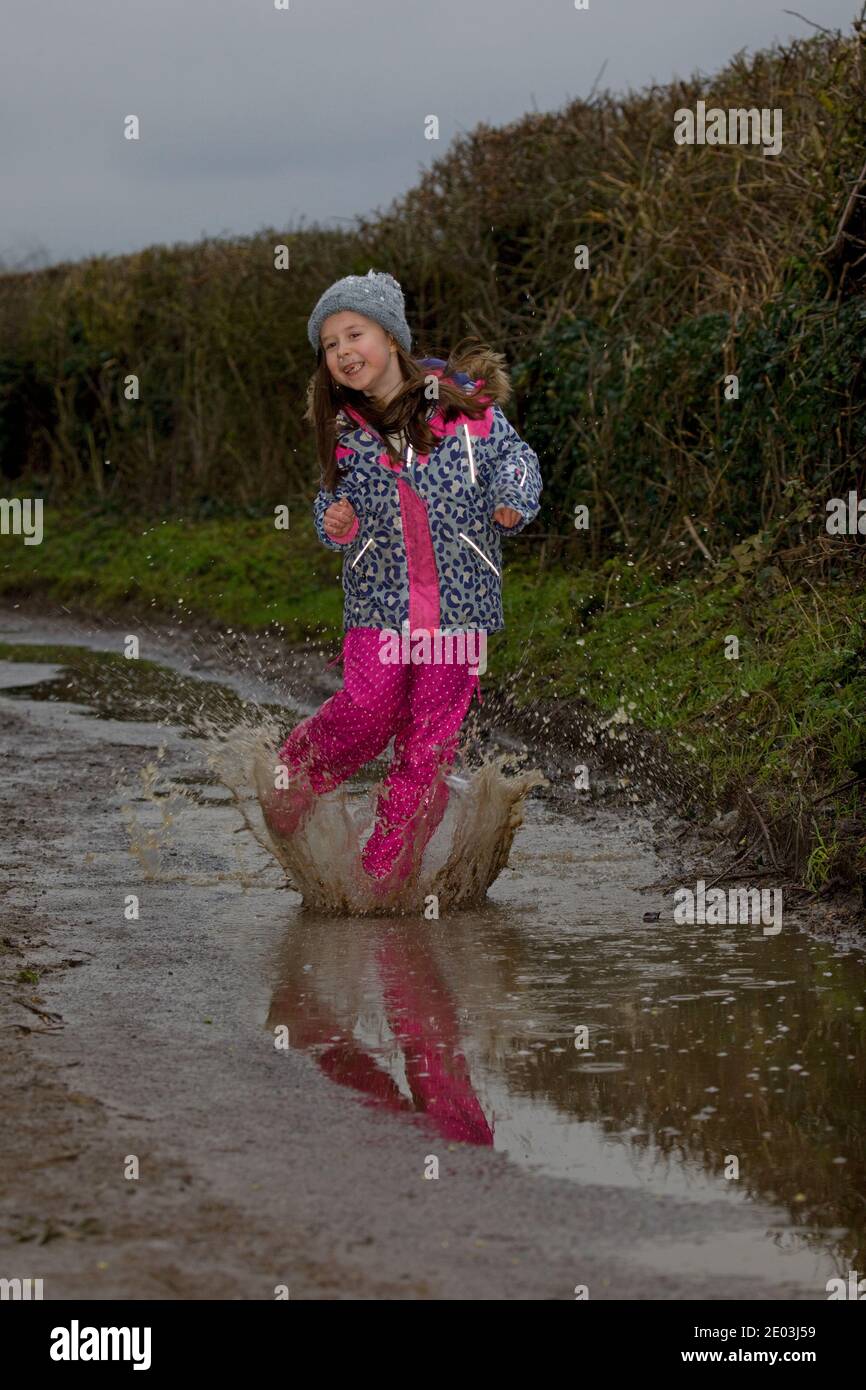 Jeune fille heureuse sautant dans des flaques boueuses. Angleterre Banque D'Images