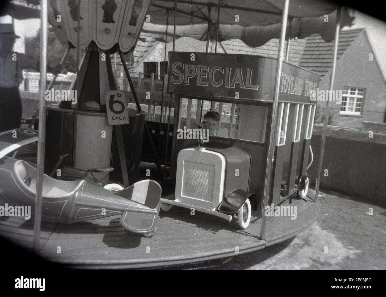 Années 1960, historique, un jeune garçon assis dans un «bus» sur un petit tour de foire, faisant semblant au chauffeur de bus, Angleterre, Royaume-Uni. Un panneau dit que le trajet coûte '6d chacun' (6 pence dans la vieille monnaie, pré-décimalisaton, ) Banque D'Images