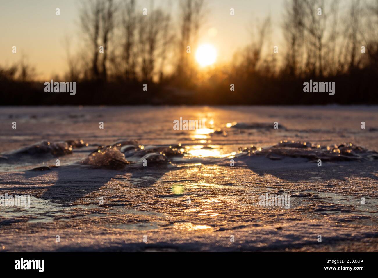 Coucher de soleil orange vif sur lac glacé glacé glacé avec faible profondeur de champ, longues ombres. Mise au point sélectionnée et arrière-plan flou Banque D'Images