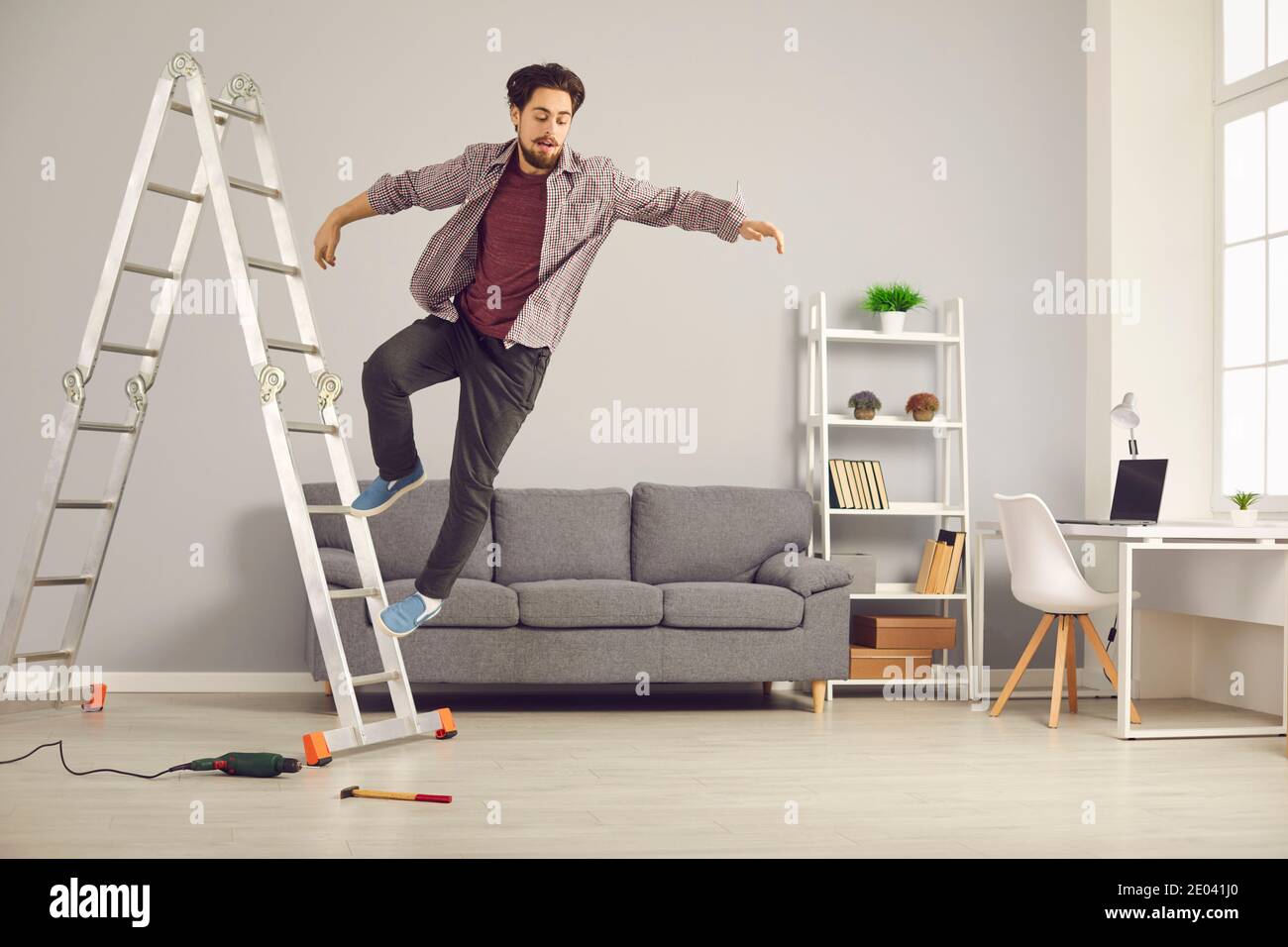 Le jeune homme malchanceux a glissé de l'échelle tout en faisant à la maison réparations et rénovation de la maison Banque D'Images