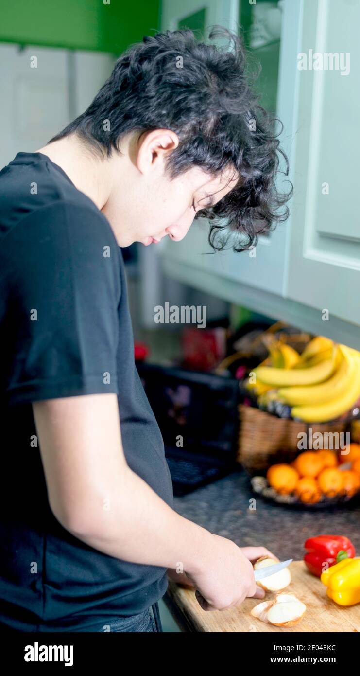 Un adolescent de race mixte prépare des légumes dans la cuisine Banque D'Images