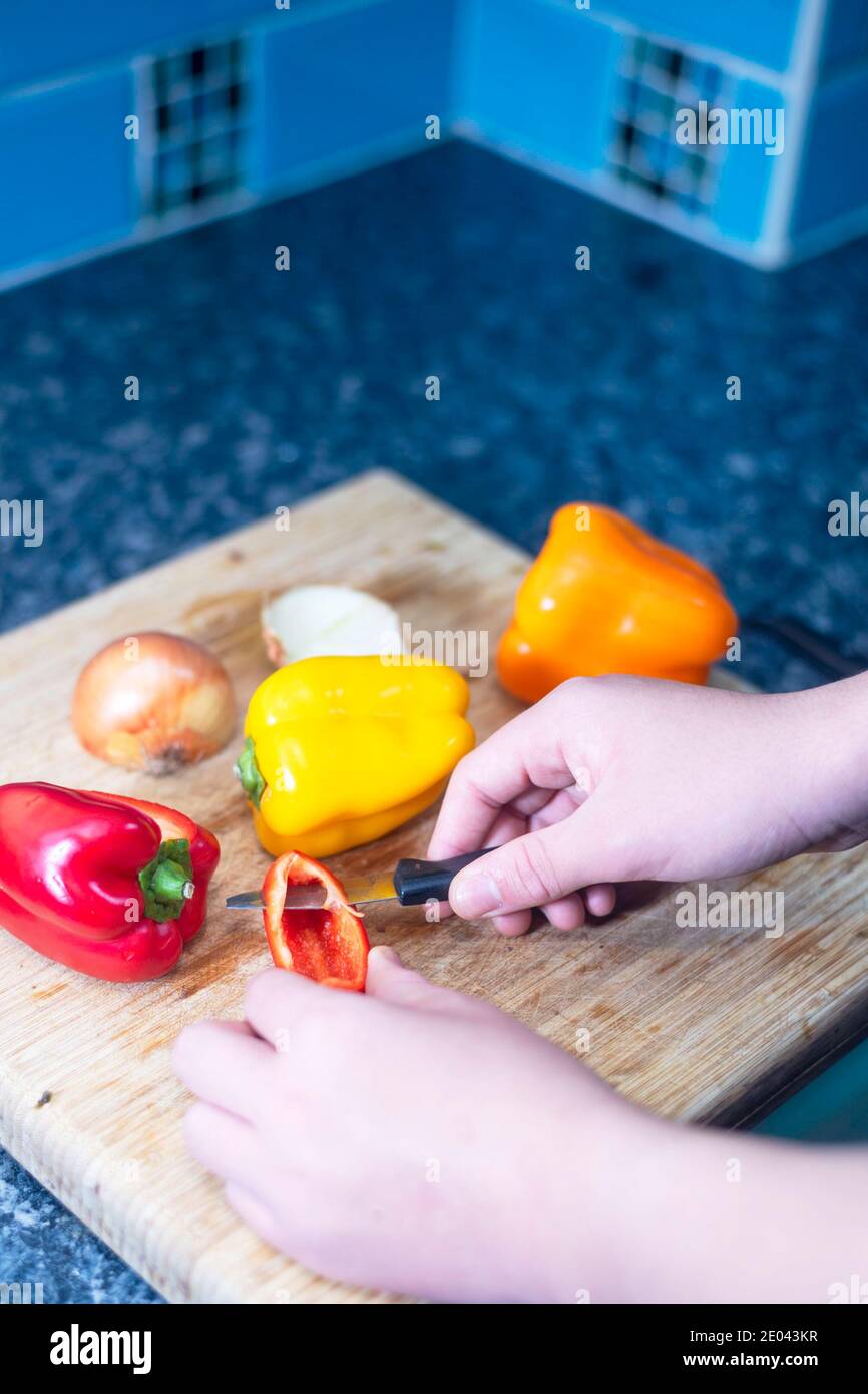 Un adolescent de race mixte prépare des légumes dans la cuisine Banque D'Images