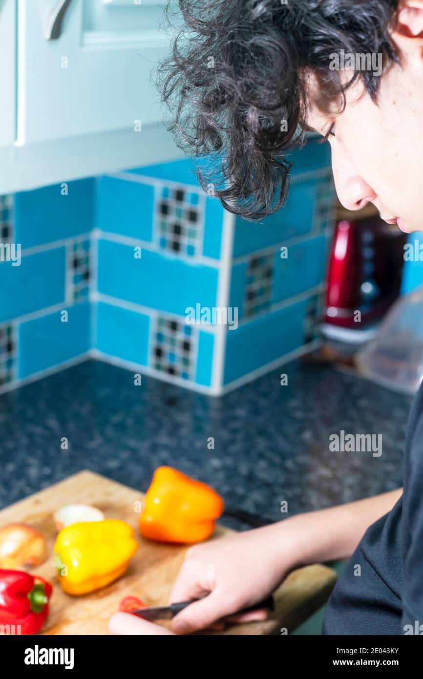 Un adolescent de race mixte prépare des légumes dans la cuisine Banque D'Images