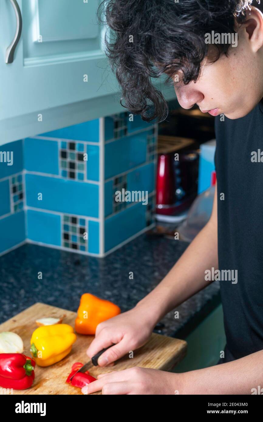 un adolescent de race mixte prépare des légumes dans la cuisine Banque D'Images