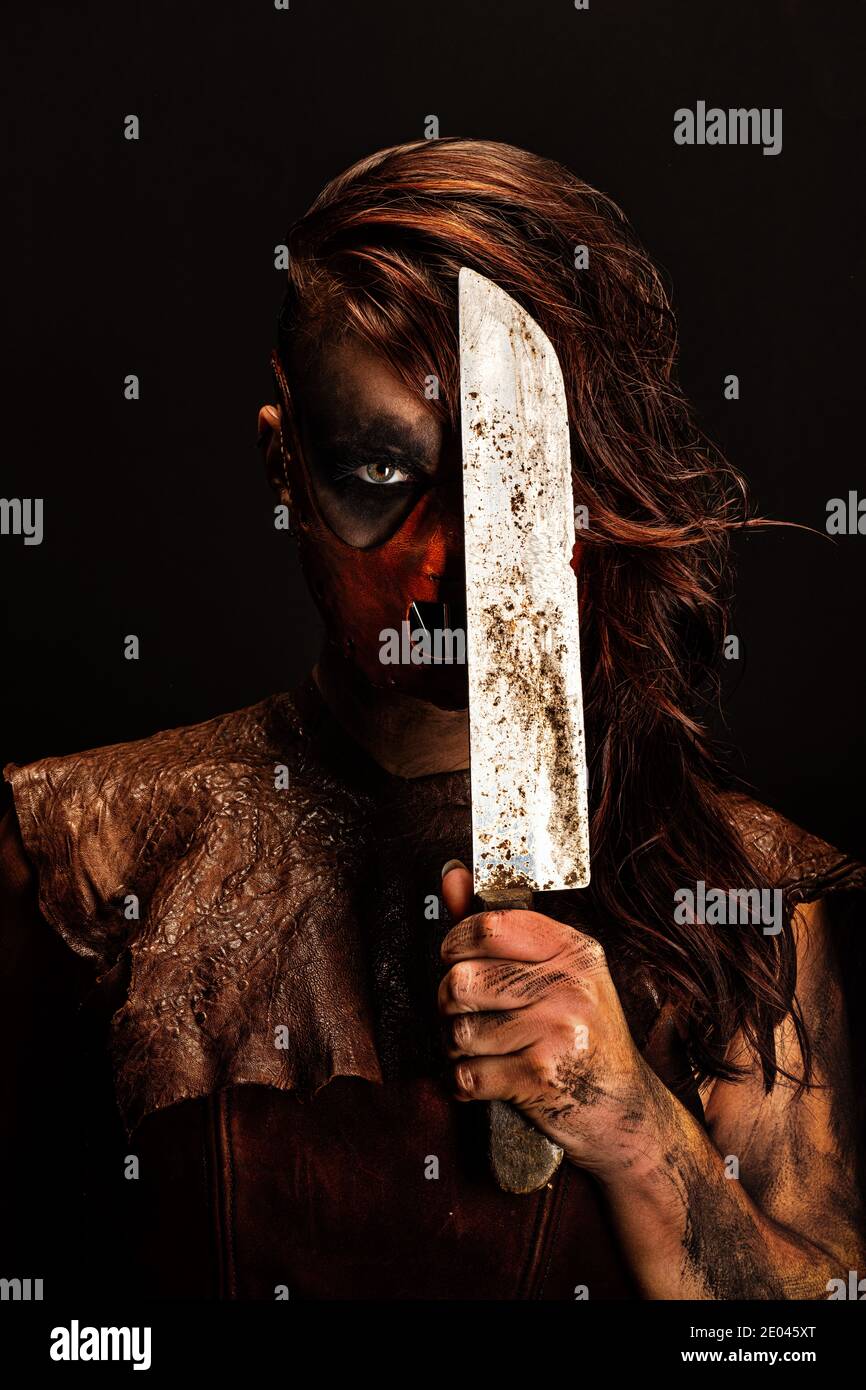 Portrait d'un sauvage meurtrier armé d'un couteau qui elle tient devant la moitié de son visage Banque D'Images