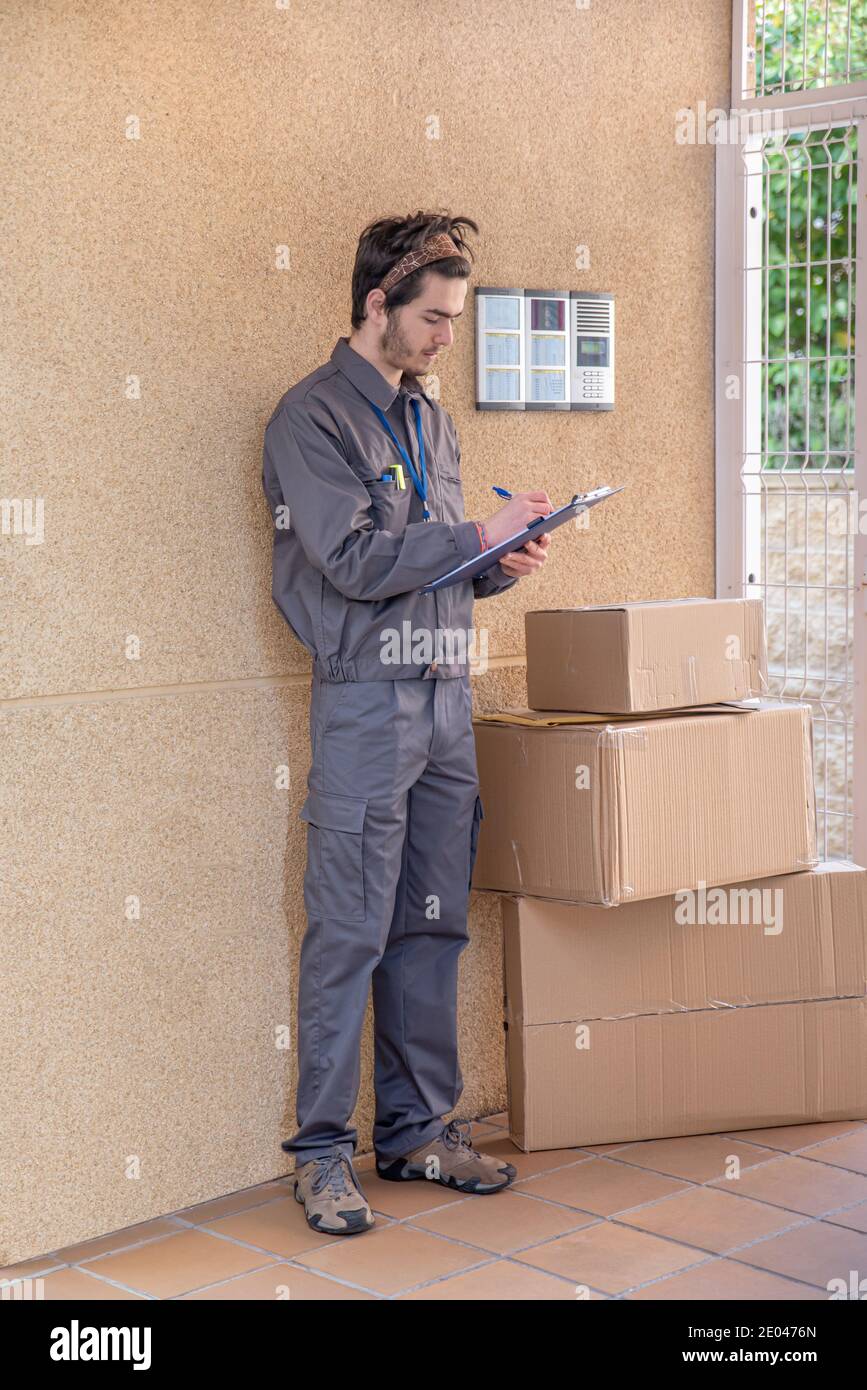 Messenger avec masque livre des paquets à la porte à côté de le portier Banque D'Images