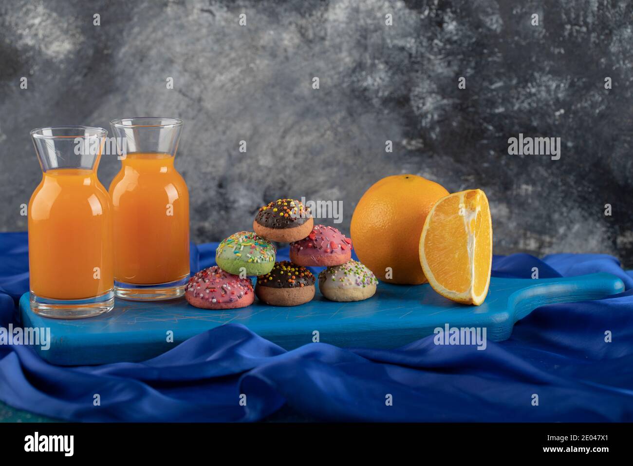 Beignets doux colorés avec des pots de jus en verre et un tasse de thé Banque D'Images