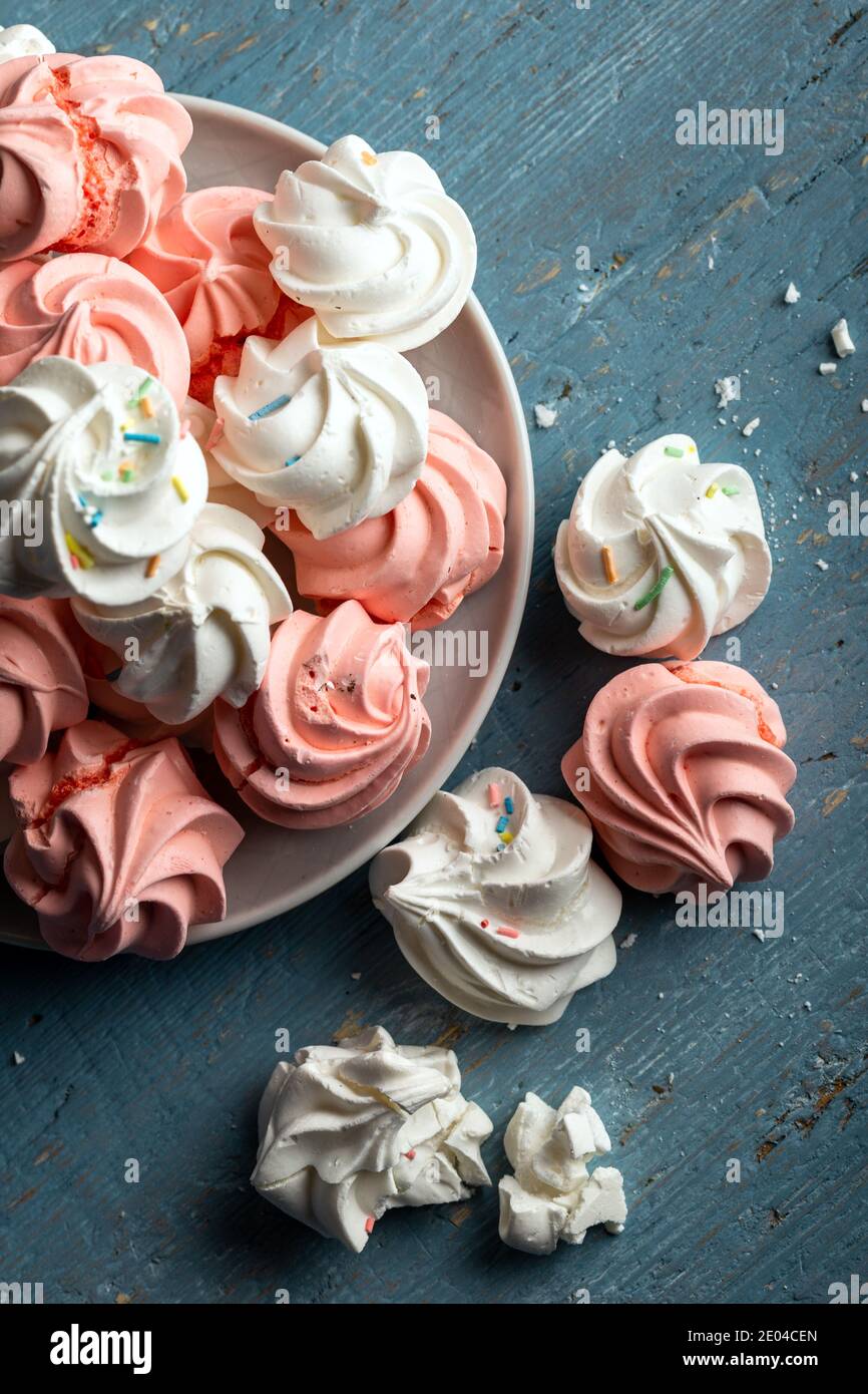 Motif avec des biscuits meringue blancs et roses délicats sur fond de bois. Banque D'Images