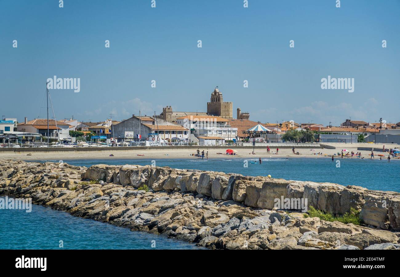 Digue portuaire de Port Saintes-Maries-de-la-Mer avec vue sur la plage Arena et l'église fortifiée en arrière-plan, département des Bouches-du-Rhône, Sou Banque D'Images