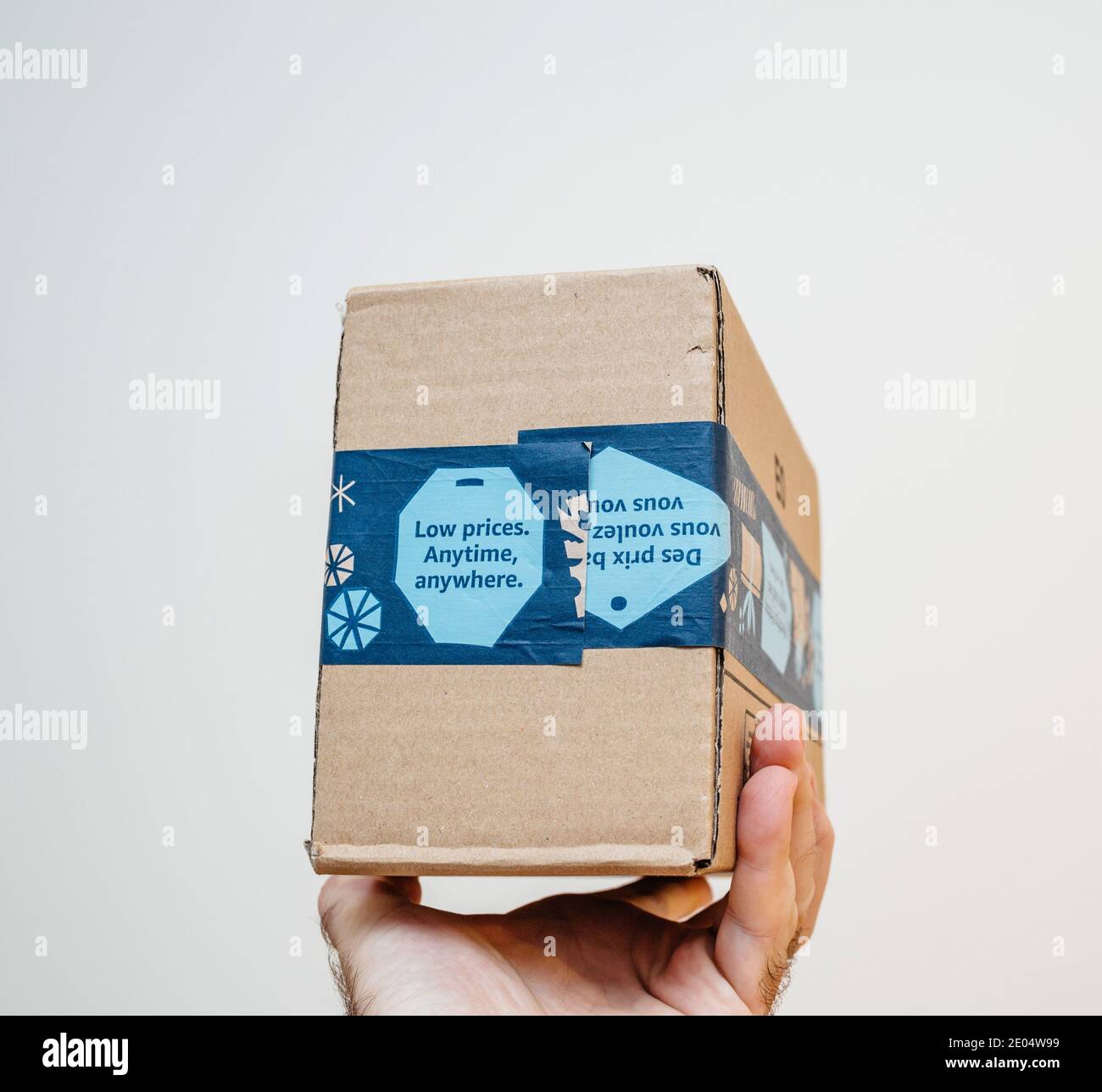 Paris, France - 12 décembre 2020: POV homme main tenant paquet de colis d' Amazon Prime avec bas prix n'importe quand, partout publicité sur le paquet  - isolé sur blanc Photo Stock - Alamy