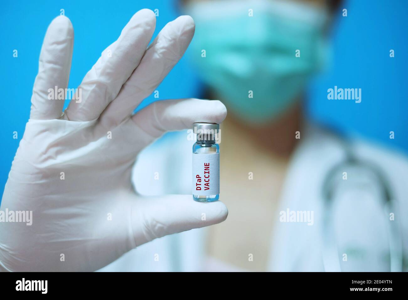 Médecin asiatique féminin avec masque chirurgical et gants en caoutchouc blanc dans une clinique, tenant une bouteille en verre de vaccin DCaT ou vis à 1 dose, avec dos blanc Banque D'Images