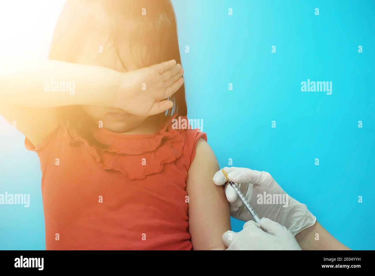 Une jeune fille asiatique mignonne qui obtient une injection de vaccin sur son bras avec une seringue et une aiguille par un médecin dans une clinique, essayant d'être courageuse mais sentant la cicatrice Banque D'Images