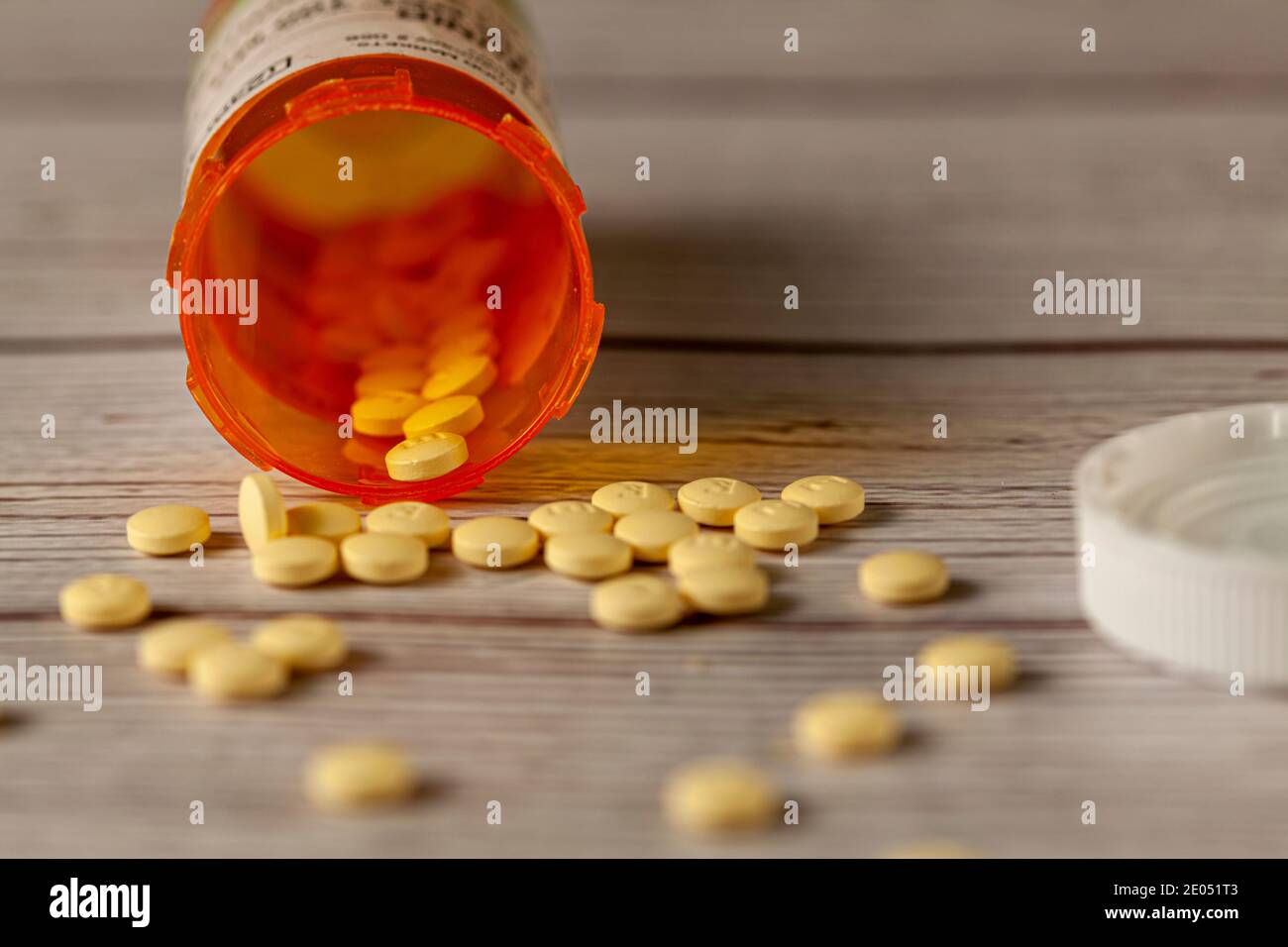 Une bouteille de médicament d'ordonnance d'orange sur la table en bois avec des pilules jaunes rondes dispersées sur la surface . Une image polyvalente pour la santé, Banque D'Images