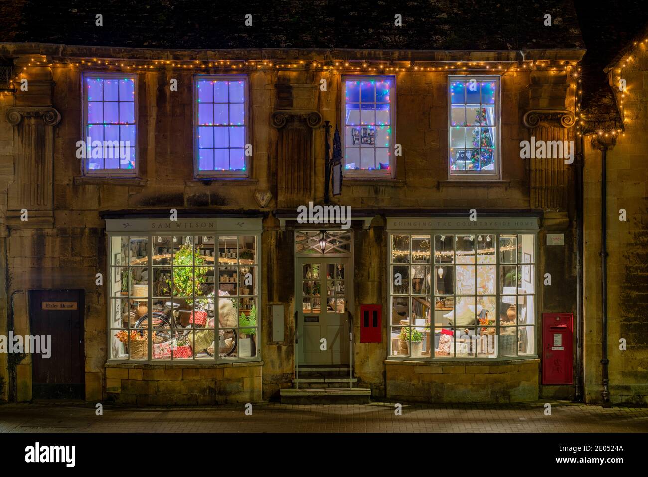 Chipping Campden High Street shop avec des lumières et des décorations de noël au crépuscule. Chipping Campden, Cotswolds, Gloucestershire, Angleterre Banque D'Images