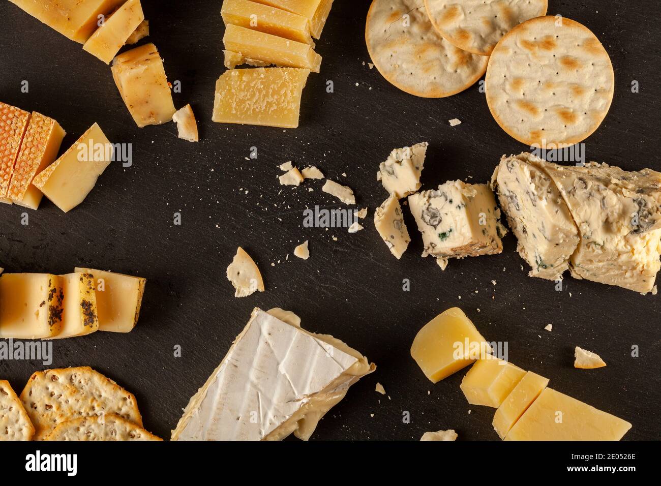 Une image de dessus d'une sélection de fromages artisanaux français, italiens et suisses âgés sur plateau de fromages noirs servis avec des craquelins. Miettes Banque D'Images